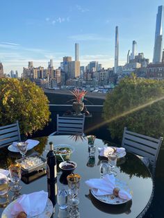 an outdoor table with plates and glasses on it overlooking the cityscape in the distance