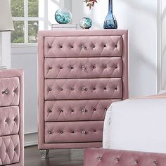 a pink dresser and bed in a room