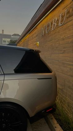 a silver car parked in front of a wooden building with nobu written on it