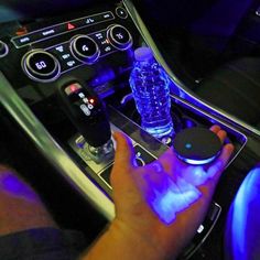 a person holding a remote control in their hand next to a car steering wheel and dashboard