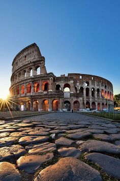 the sun shines brightly in front of an old roman colossion at sunset