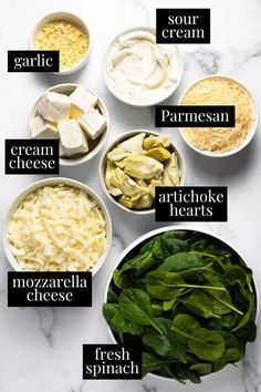 the ingredients for spinach salad laid out in bowls on a white marble counter top