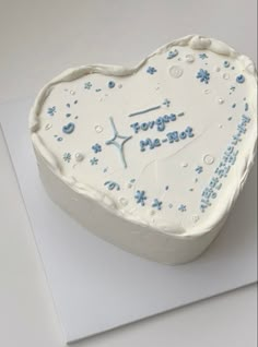 a white heart shaped cake with blue frosting