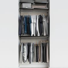 an organized closet with clothes hanging on the racks and folded shirts in front of it