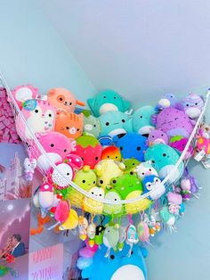 a bunch of stuffed animals are hanging from the ceiling in front of a wall with pictures on it