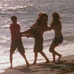 three people on the beach playing with each other