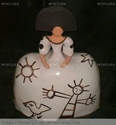 a ceramic figurine sitting on top of a white vase with black and white designs