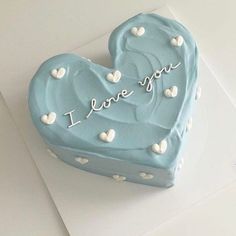 a heart shaped cake with the words i love you written on it and white hearts