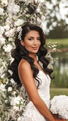 a woman in a wedding dress standing under a flower covered arch with flowers on it