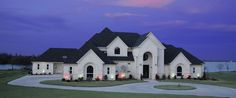 a large white house with lots of lights on it's front yard and driveway