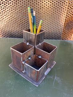 three metal containers with pencils and pens in them