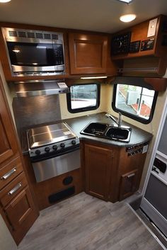 an rv kitchen with wood cabinets and stainless steel appliances, including a stove top oven