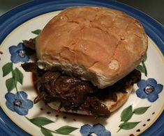 a pulled pork sandwich on a plate with blue flowers