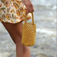 Vacation season is never complete without a novelty bag to create picture-perfect Instagram shots. Introducing GOLDA, the ultra-desirable bucket bag with the Bali X Cali-infused style. Feel nature’s energy in the palm of your hand as you tote the GOLDA Metallic Beads Bucket bag in gold beads color on a sunny day at the beach. The shimmering metallic beads reflect the sunlight, creating a beautiful play of light and color. Completed with a drawstring pouch to keep your belongings secure, GOLDA Me Beaded Bucket Bag, Create Picture, Ethical Fashion Brands, Tropical Getaways, Novelty Bags, Drawstring Pouch, Women Artisans, Small Wallet, Photo Instagram