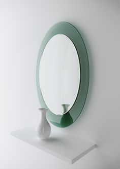 a white vase sitting next to a round mirror