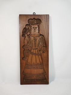 a wooden plaque with an image of a woman wearing a dress and holding a flower