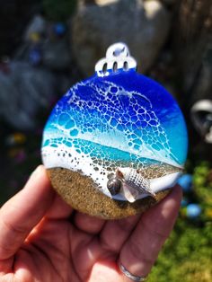 a hand holding a blue and white glass ornament in it's palm