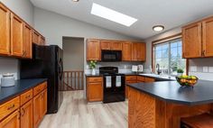 a large kitchen with wooden cabinets and black counter tops, along with hardwood flooring