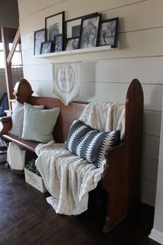 a wooden bench with pillows and pictures on the wall