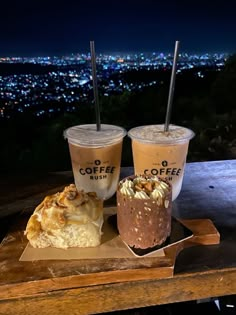 three drinks are sitting on top of a wooden table in front of the city lights