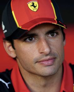 a close up of a person wearing a red and black hat with a ferrari logo on it