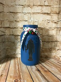 a blue jar sitting on top of a wooden table next to a brick wall with a silhouette of a man