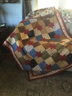 a quilted blanket sitting on top of a couch in a living room next to a window