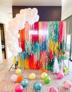 balloons, streamers and streamers are on the floor in front of a colorful backdrop