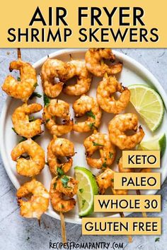 grilled shrimp skewers on a white plate with lime wedges and cilantro