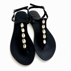 Black sandals with sea shells, Greek leather sandals, Cowrie shells black sandals, Summer sandals, Beach sandals, Handmade leather sandals Elegant leather sandals, a must have accessory for the summer. They could be perfect for any woman who wants to make a difference & wear something special every day. *All sandals are made of Genuine Greek Leather! *You'll receive it in a handmade cotton bag *The sandals are shipped with a tracking number!          Handmade in Greece Please note that they get Black Leather Flip Flops For Beach Season, Black Sandals For Beach Season, Summer Black Slingback Sandals For Beach Season, Black Slingback Sandals For Beach, Black Adjustable Slingback Summer Sandals, Black Beach Season Sandals With Single Toe Strap, Black Sandals With Single Toe Strap For Beach Season, Black Single Toe Strap Sandals For Beach Season, Beach T-strap Sandals With Single Toe Strap