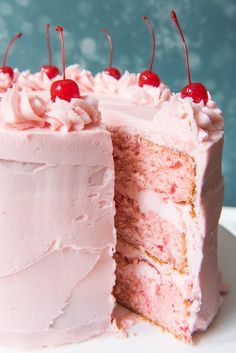 a cake with pink frosting and cherries on top