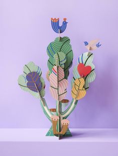 an origami tree with birds and flowers in it on a purple background, cut out from paper