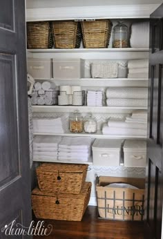 an organized closet with baskets, towels and other items on the shelving in it