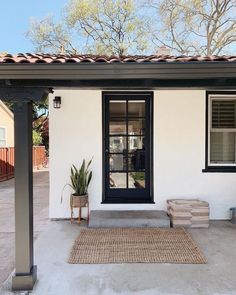 a small white house with a black front door and two planters on the porch