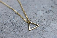 A 16K gold plated triangle, hangs on a delicate 16K gold plated chain, making a simple but elegant statement. The perfect layering piece or minimalist necklace.  The triangle measures half of an inch (14mm) and you decide the length of the chain. If you would like a chain length not offered, simply write it in the notes at the time of purchase. Add a 2" extender chain to give you flexibility in length! Ex. If you choose a 16" chain, you would be able to wear the necklace any length from 16"- 18" Minimalist Gold Triangle Jewelry, Minimalist Triangle Gold Jewelry, Minimalist Triangle Brass Jewelry, Layered Necklaces Boho, Diamond Charm Necklace, Dainty Necklace Layered, Rectangle Necklace, Minimalist Necklace Gold, Wooden Bead Necklaces