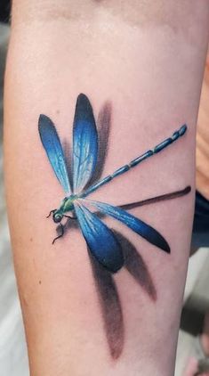 a blue dragonfly tattoo on the arm