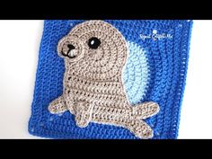 a crocheted square with a seal on it's side and a blue border