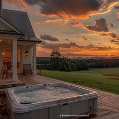 a hot tub sitting on top of a wooden deck next to a large white house