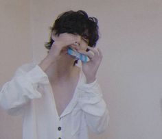 a woman brushing her teeth in front of a mirror with one hand and the other holding a toothbrush up to her face