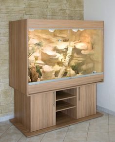 a fish tank sitting on top of a wooden cabinet next to a brick wall and tiled floor