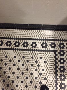 a person's feet are standing on the floor in front of a black and white tile pattern