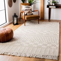 a living room area with a chair, rug and potted plant on the floor