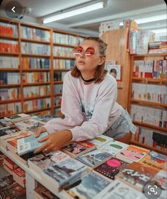 a woman sitting at a table covered in books