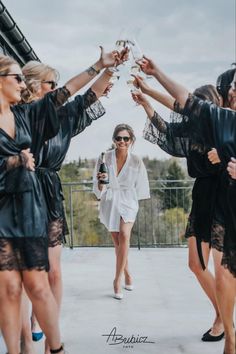 a group of women standing around each other holding wine glasses in the air with their hands