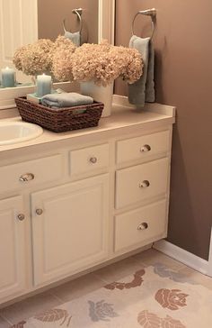 a bathroom vanity with flowers and candles on it