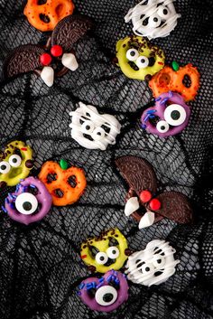 halloween decorated donuts on a mesh tablecloth with eyes and mouth decorations in the shape of bats