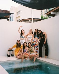 four women are posing in front of a swimming pool