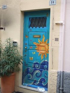 a blue door with sun and clouds painted on the side next to a potted plant