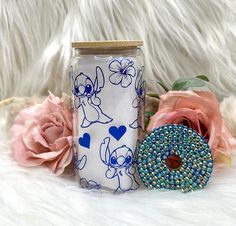 a cookie jar next to a pink flower and a blue beaded donut on a white furnishing