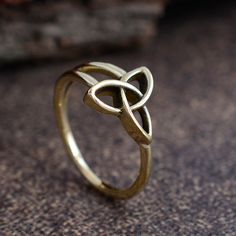 a gold ring with an intertwined knot on it's side, sitting on the ground